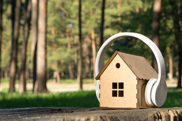 Toy house with headphones on top on a tree stump