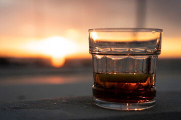 Glass of double malt whiskey with ice cubes - Beautiful sunset at the background