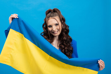 Woman on blue background, wearing jacket holds Ukrainian flag, smile, gaining freedom, regaining...