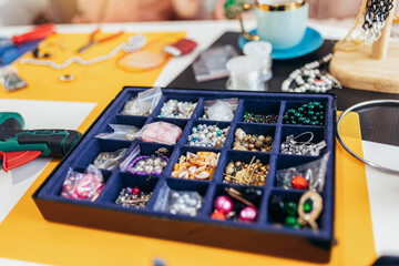 Box with beads, spool of thread, plier to create hand made jewelry on old wooden background. Making bracelet. Handmade accessories.