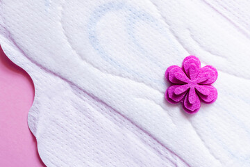 close up of white panty liner with purple flower on violet background, top view.