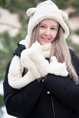 Beautiful teen girl in a fur hat looks at the camera and smiles.