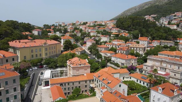Aerial drone forwarding shot of Lastovo, a small town on hill top near the coastline, Dubrovnik province, Croatia at daytime. buildings on both sides of the road over hilly terrain.