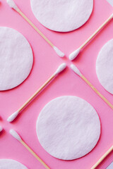 close up of ear sticks and cotton pads on pink background, top view.