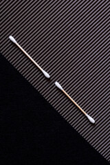 top view of two cotton swabs on textured and black background.