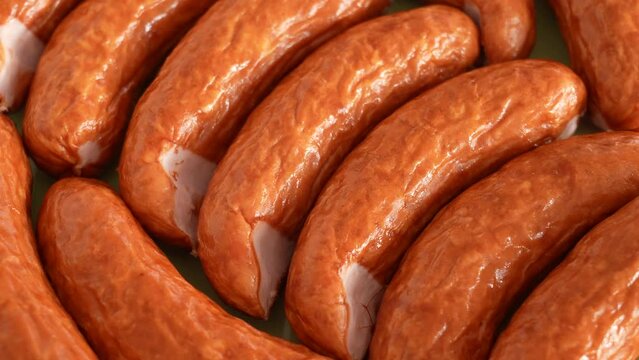 Closeup view 4k stock video footage of organic smoked sausages isolated on green plate background