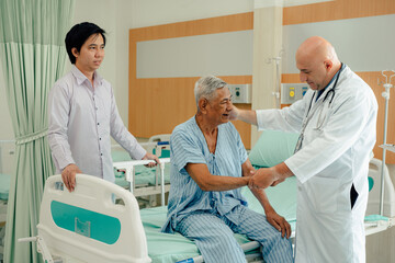 Obraz premium Hospitalized man sitting in bed while doctor checking his pulse. Doctor examining senior male patient in hospital room.