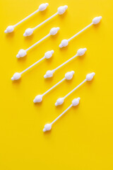 top view of cosmetic cotton swabs on bright yellow background.