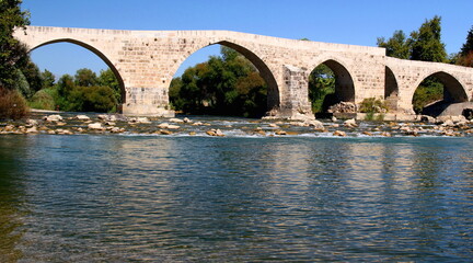 Five-arch stone Historic Aspendos Bridge across the river surrounded by picturesque nature near Antalya, Turkey