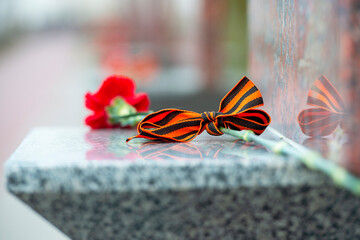 Ribbon of Saint George and carnation on a tombstone in Russia