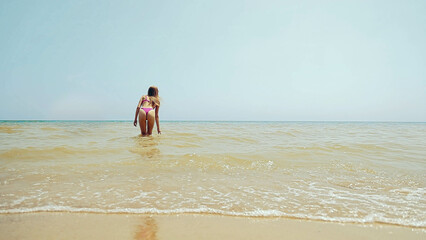 One young girl in a bathing suit bathes herself in the sea. Bath