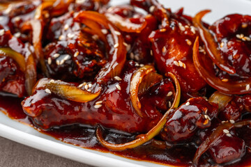 ayam goreng mentega or fried chicken with soy sauce, butter and onion served on white plate.
