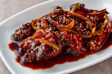 ayam goreng mentega or fried chicken with soy sauce, butter and onion served on white plate.