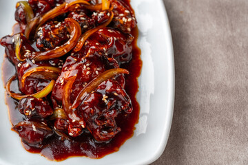 ayam goreng mentega or fried chicken with soy sauce, butter and onion served on white plate.