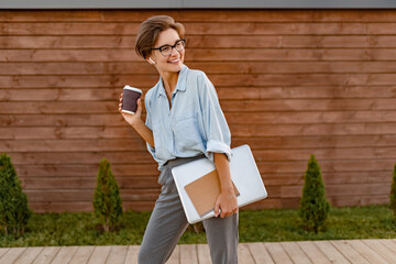young pretty woman sitting with laptop in modern park street