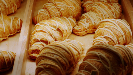 In front of the camera in the bakery cafe taking video closeup of fresh french croissants from the showcase fridge