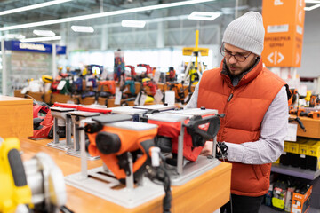 a man in a supermarket in the department of electrical goods chooses an electric planer