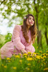 a young woman in a pink dress posing next to a blossoming apple, spring portrait.