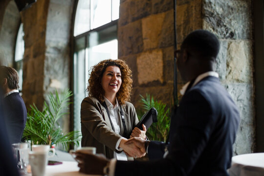 Businesswoman shaking hand with businessman at seminar in convention center