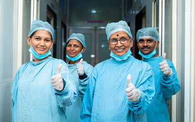 smiling group of surgeons showing thumbs up while at hosiptal corridor after surgery - concept of successful treatment, medical practitioners and heatlhcare professionals