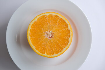 ripe and juicy orange. fresh orange cut in half on a white plate