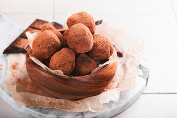 Chocolate truffles with cocoa powder in wooden dish on old cracked tile table background. Tasty sweet chocolate truffles candies. Valentine's Day and Mother's Day concept with copy space. Top view.