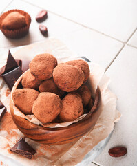 Chocolate truffles with cocoa powder in wooden dish on old cracked tile table background. Tasty sweet chocolate truffles candies. Valentine's Day and Mother's Day concept with copy space. Top view.