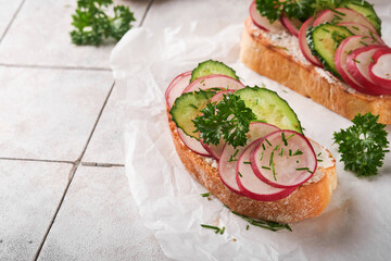 Toast with cheese and radish. Sandwiches with cottage cheese, radish, cucumber and green onions on old cracked tile background. Healthy spring sandwiches. Traditional Scandinavian toast. Top view.