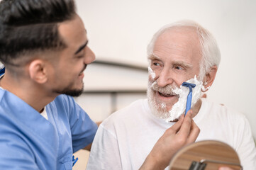Caring volunteer giving an elderly gentleman a shave