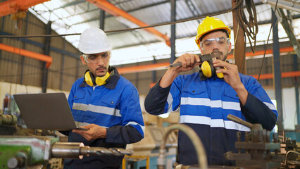 Factory engineer measure steel tube by using vernier caliper. Checking or maintenance machine. Wearing safety helmet and glasses during work. Worker inspector equipment. Industrial and technology