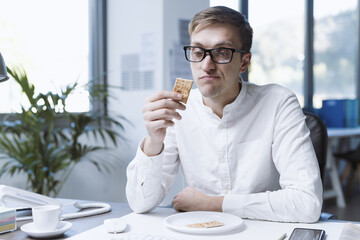 Sad office worker eating a very small meal