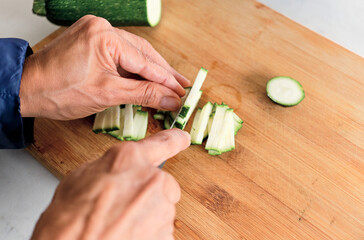 person slicing cucumber with short knife