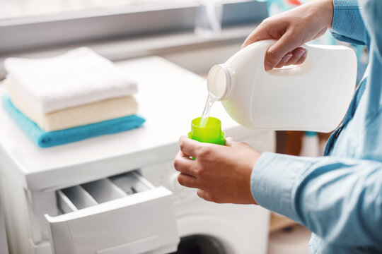 A housewife carefully doses the detergent to put in the washing machine