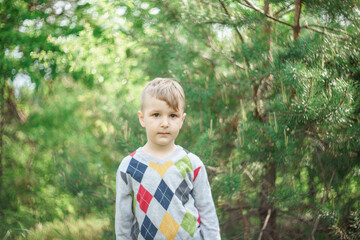 portrait of a blond boy outside in natural light, the boy staring straight into the camera