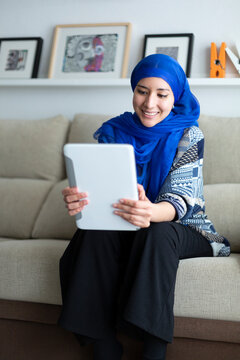 Smiling Young Muslim Woman Using A Digital Tablet At Home. Technology And Lifestyle.