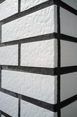 Corner of the house is neatly tiled, outwardly resembling white brick. Textured background. 