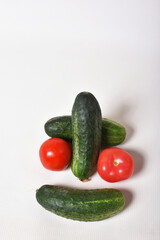 Cucumbers and tomatoes as a smiley face on a white table
