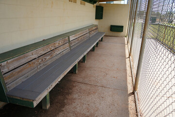 Empty Baseball Field Dugout with bench and fence.     