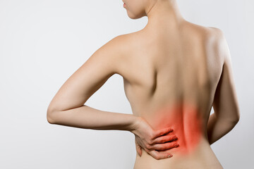 Naklejka premium Woman having backache, pain back isolated on gray background. Scoliosis. Spinal cord problems on womans back. Woman touching her back