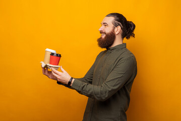 Side view photo of a man holding two take away cups of coffee in a holder.