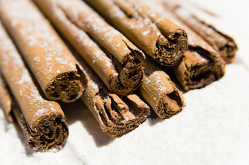 Stack of dry cinnamon with icing sugar as snow on a white background