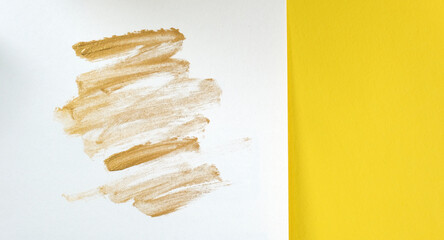 Gold metallic makeup streaks on white background with copy space on yellow color for beauty concept.