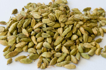 Heap of dry green cardamons on a white background
