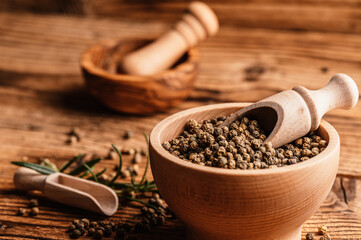 Black pepper in wood bowl on wooden table. Spices on desk. Organic spice dry peppercorn.