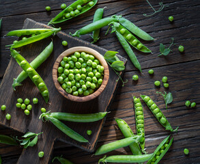 Green peas and pea pods on wooden table. Top view.