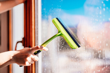 Woman clean a window with cleaning sprayer. Housekeeping concept. Girl hold in hand cleaning...