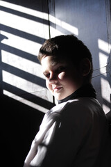Portrait of a handsome young boy from Cuba in a window shade in sunlight