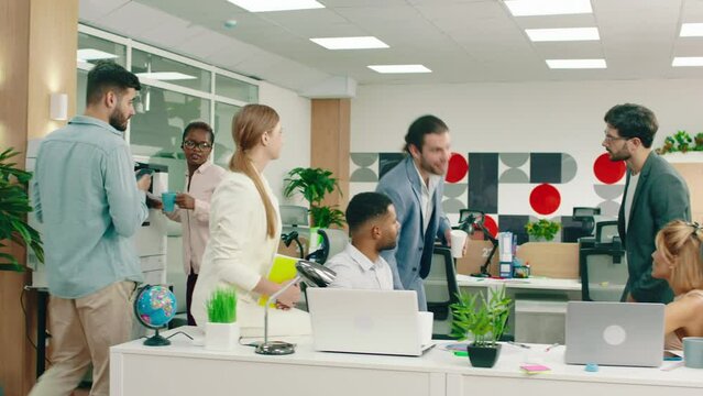 A handsome and intelligent man wearing a nice blue suit caring a briefcase walks into an office meeting and greets everyone with a smile, he starts to talk during the meeting. Arri Alexa Mini.