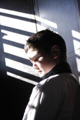 Portrait of a handsome young boy from Cuba in a window shade in sunlight