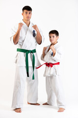 Young man and karate boy in fudo dachi position on white background. With the word kyokushinkai on the background. Which means: the last truth associated.